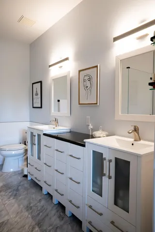 a spacious bathroom with a double vanity sink a mirror and a toilet