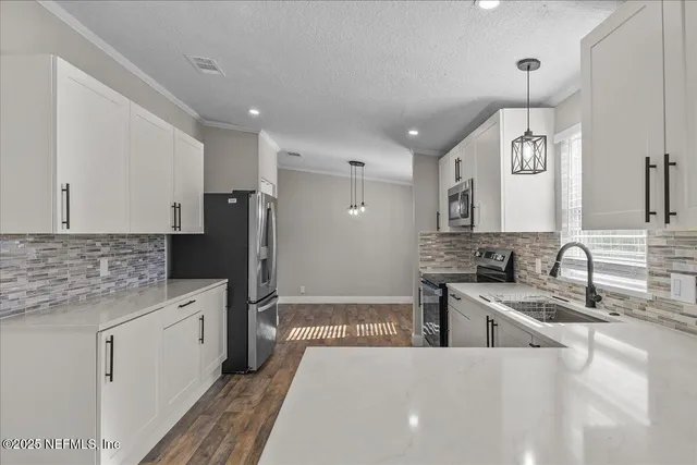 a large white kitchen with a refrigerator a stove and a sink