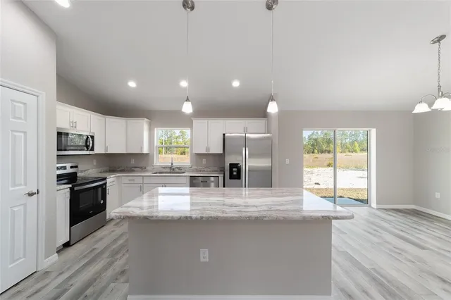 a large kitchen with granite countertop a large kitchen island sink stainless steel appliances and cabinets