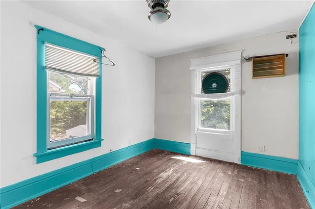 a view of an empty room with window and wooden floor