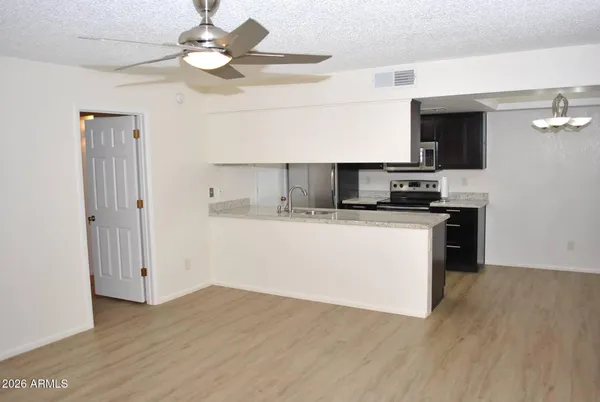 a kitchen with stainless steel appliances a stove top oven a sink a microwave a refrigerator and white cabinets