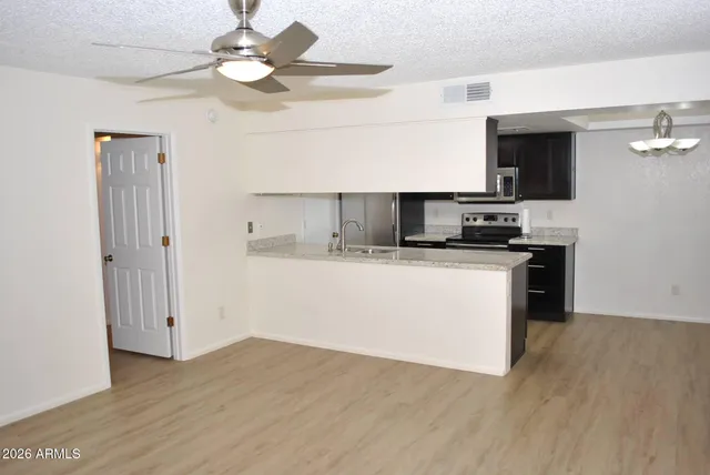 a kitchen with stainless steel appliances a stove top oven a sink a microwave a refrigerator and white cabinets