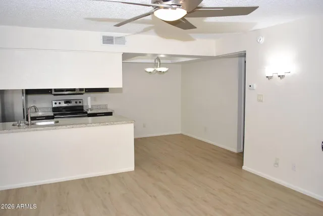 a living room with stainless steel appliances kitchen island a sink and wooden floor