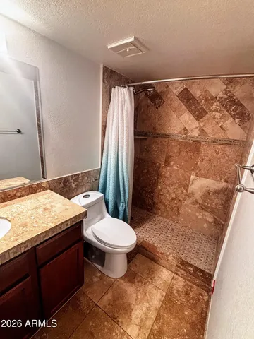 a bathroom with a granite countertop sink toilet and shower