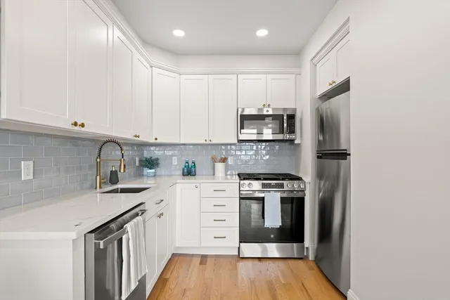 a kitchen with stainless steel appliances granite countertop a stove top oven a sink and dishwasher a refrigerator with wooden floor