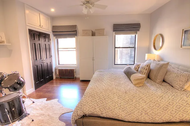 a bedroom with a bed a mirror and a wooden floor