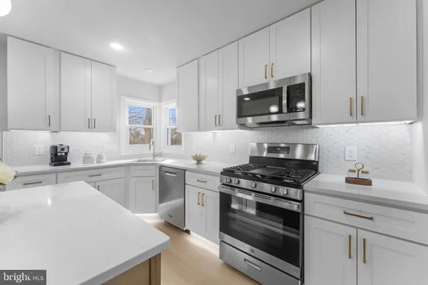 a kitchen with stainless steel appliances white cabinets and stove top oven