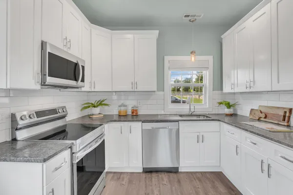a kitchen with granite countertop white cabinets sink and stainless steel appliances