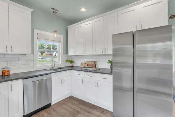 a kitchen with granite countertop white cabinets white appliances and sink