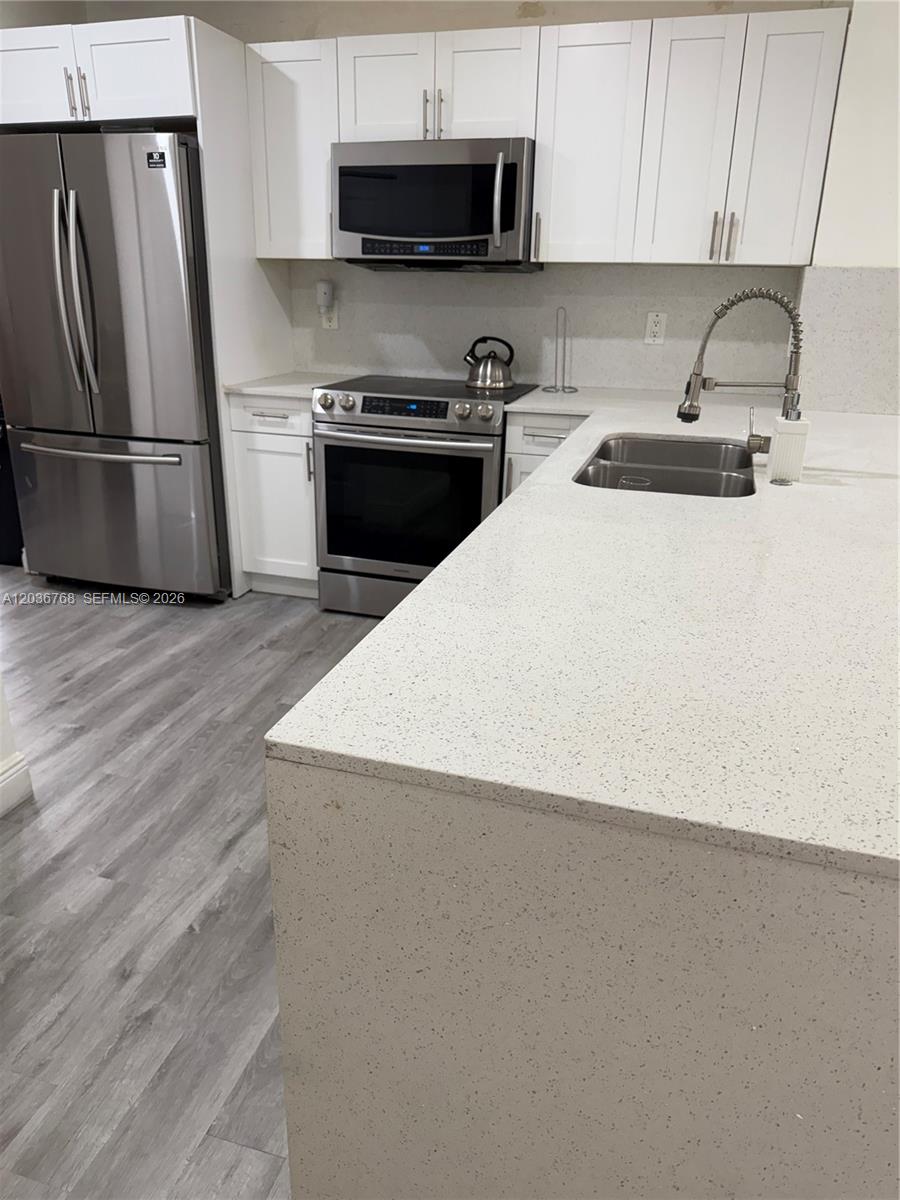 2432 Southwest 99th Way Miramar, FL 33025 - Photo 17 of 17 a kitchen with stainless steel appliances a refrigerator a sink a stove a microwave and cabinets