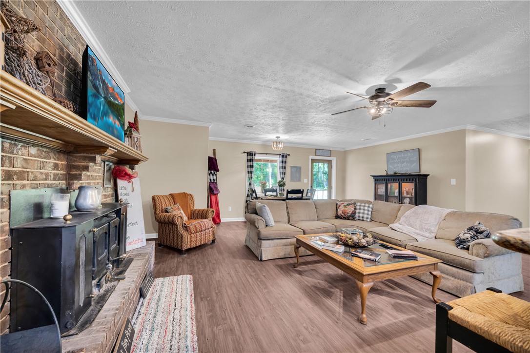 3030 Smith McGee Road Iva, SC 29655 - Photo 16 of 46 A well-lit gathering space features a substantial brick fireplace and durable wood-look flooring.
