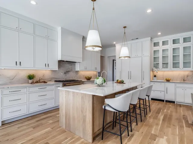 a kitchen with stainless steel appliances kitchen island a refrigerator and white cabinets