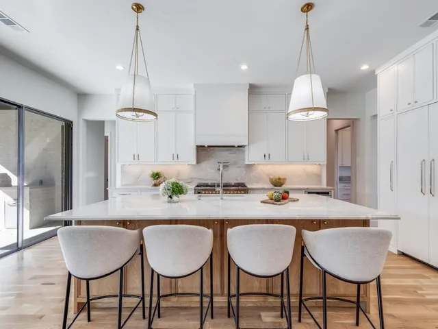 a kitchen with granite countertop a dining table chairs and white cabinets