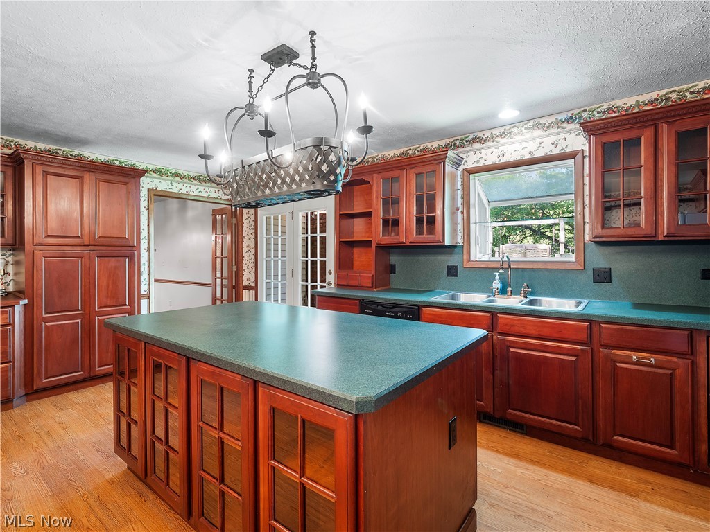 4094 Stoney Ridge Road Avon, OH 44011 - Photo 23 of 36 Kitchen featuring light hardwood / wood-style flooring, pendant lighting, an inviting chandelier, a kitchen island, and sink