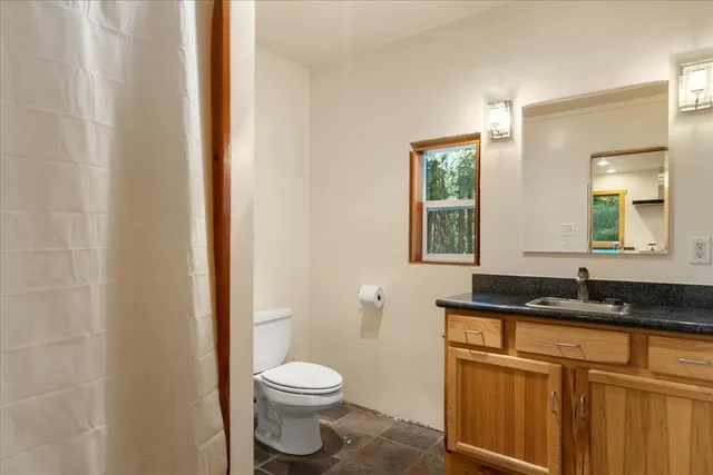 a bathroom with a granite countertop sink a toilet and a mirror