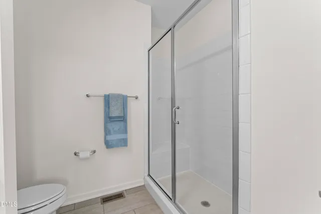 an empty room with wooden floor kitchen view and a window