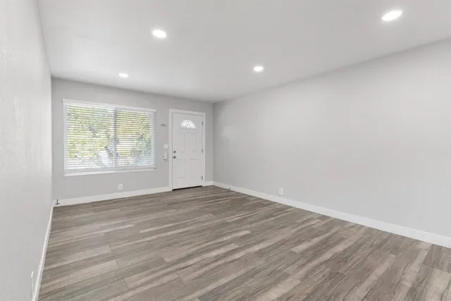 an empty room with wooden floor and windows