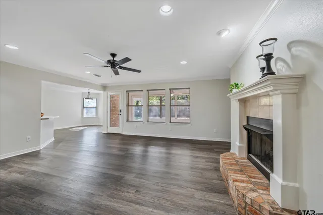 an empty room with wooden floor fireplace and windows