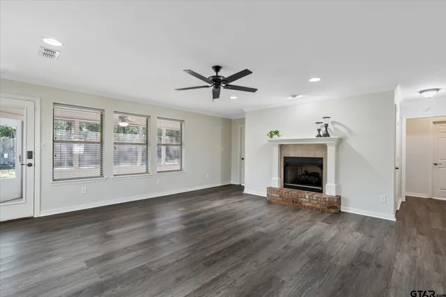 an empty room with fireplace wooden floor and windows