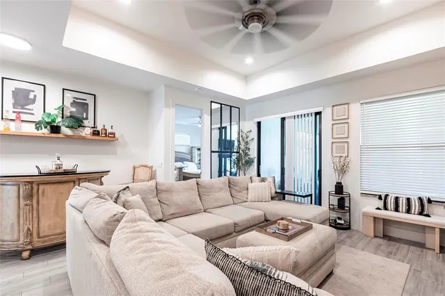 a living room with furniture ceiling fan and a large window