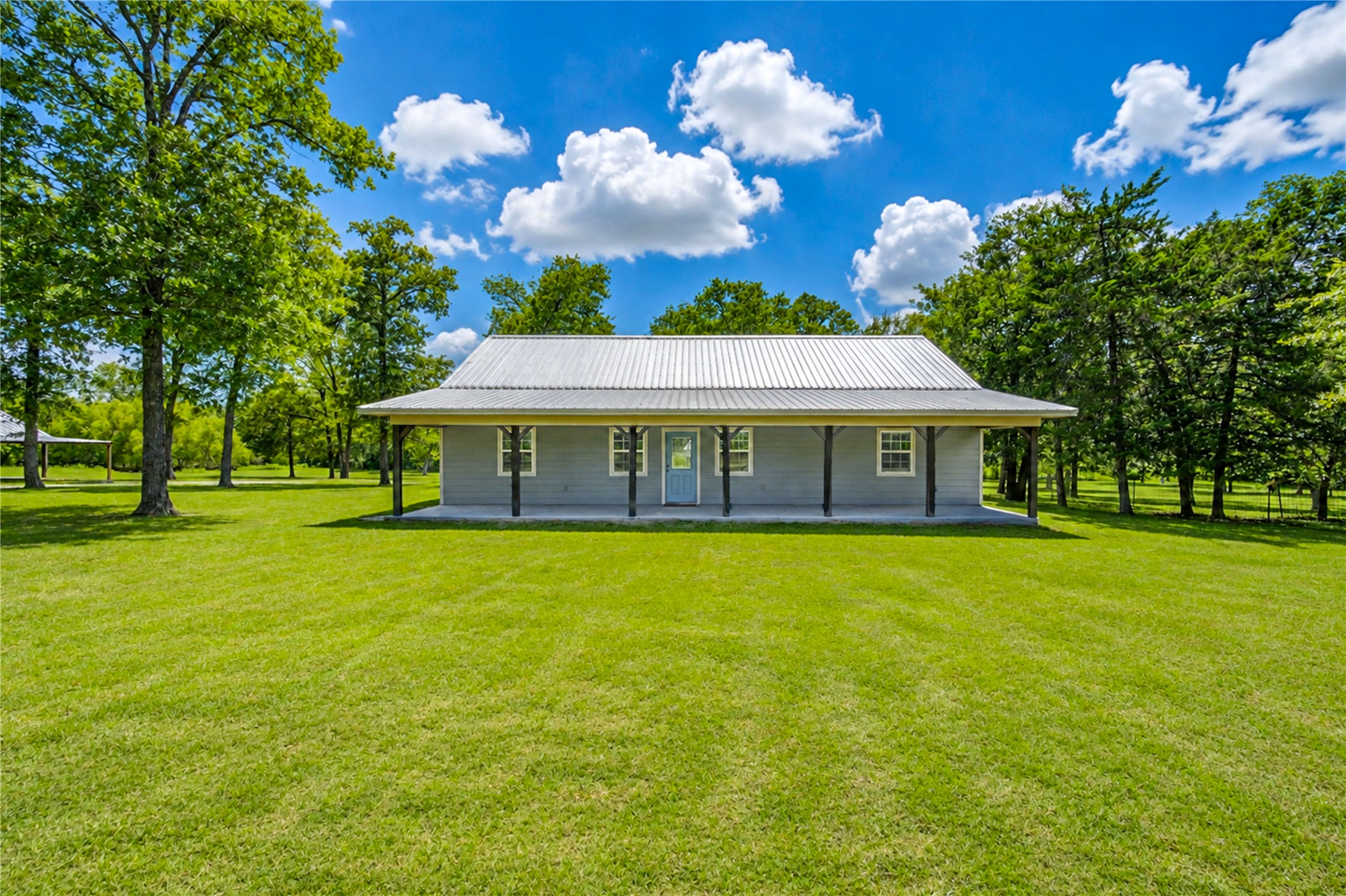 8805 Sun Oil Road Brenham, TX 77833 - Photo 1 of 50 Charming single-story home with a spacious front porch, nestled on a lush, expansive lawn surrounded by mature trees.