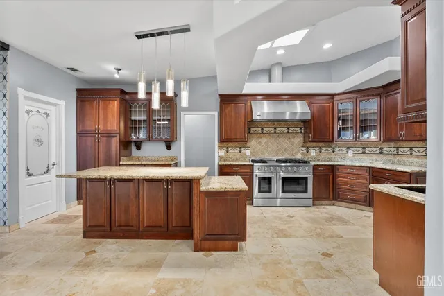 a large kitchen with stainless steel appliances kitchen island granite countertop a stove and cabinets