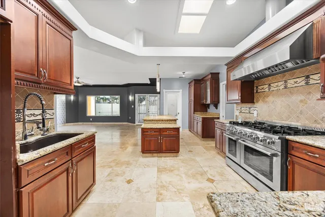 a kitchen with stainless steel appliances granite countertop a stove top oven a sink a dining table and chairs with wooden floor