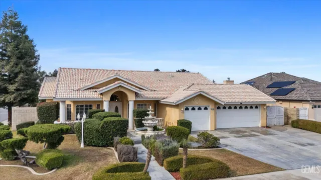 a view of a white house with a large windows plants and large trees