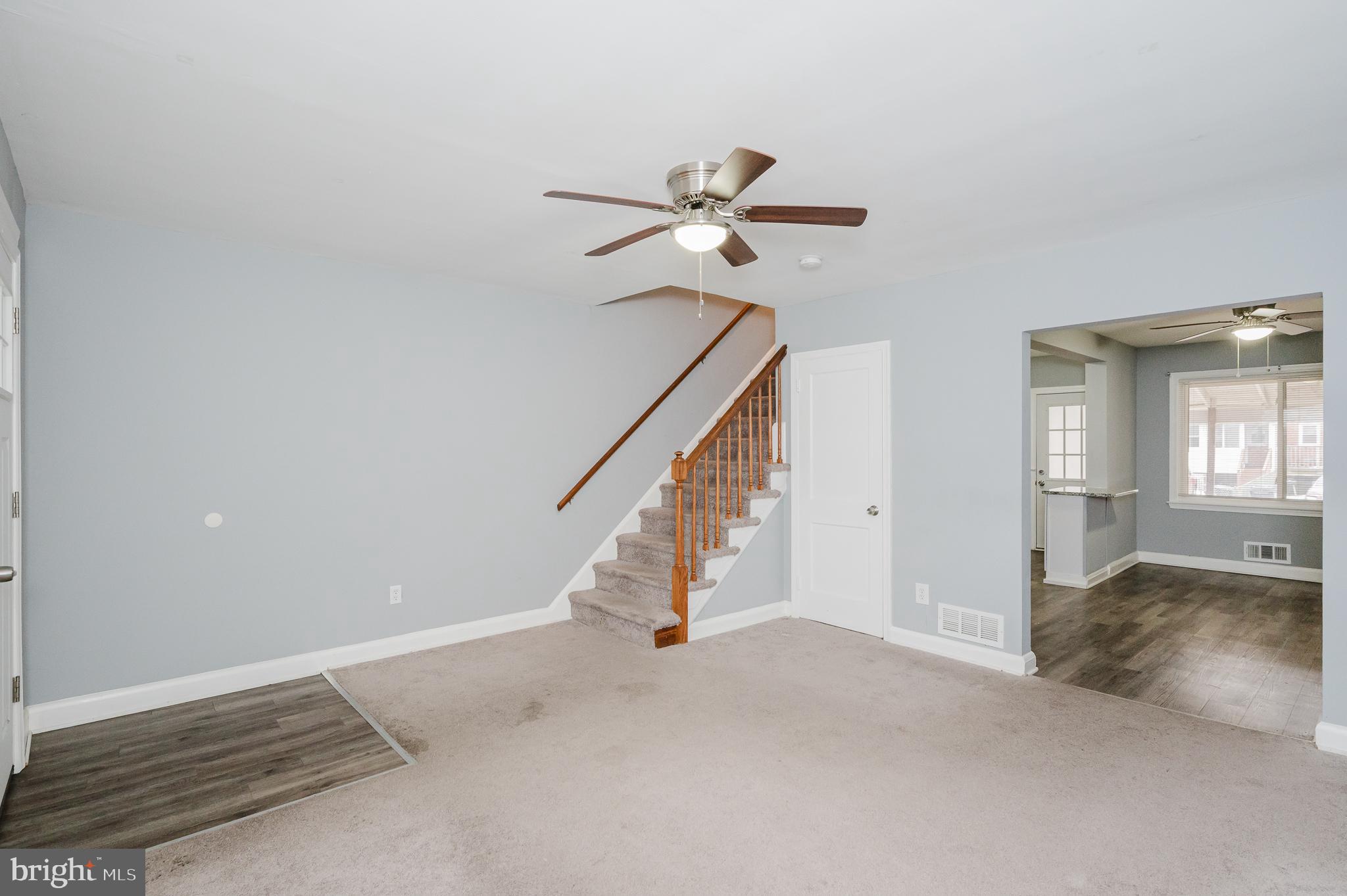 Spacious living area with inviting staircase.