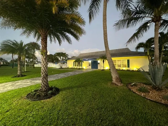 a view of a big yard with a fountain and large trees