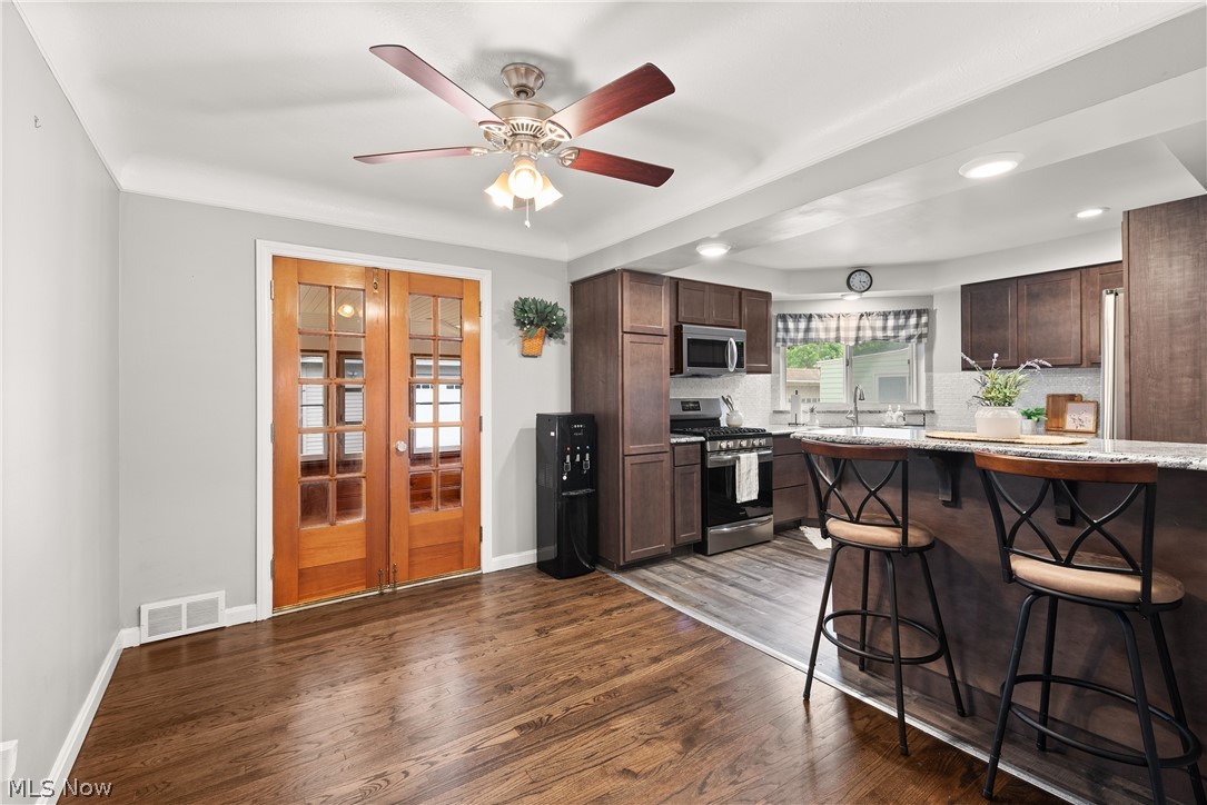21779 Eaton Road Cleveland, OH 44126 - Photo 14 of 46 Kitchen featuring dark hardwood / wood-style flooring, stainless steel appliances, backsplash, ceiling fan, and a breakfast bar