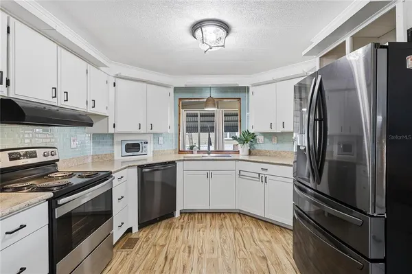 a kitchen with granite countertop stainless steel appliances a sink cabinets and a window