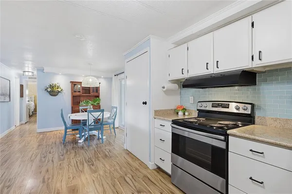 a kitchen with granite countertop wooden floors stainless steel appliances and white cabinets