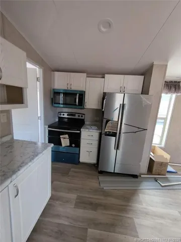 a kitchen with granite countertop a refrigerator a sink a stove a microwave and island