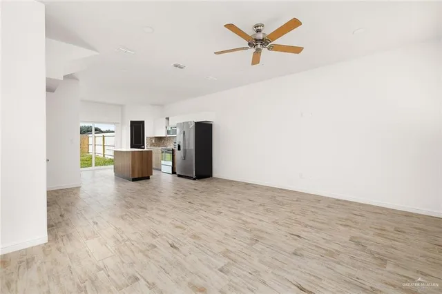 a view of kitchen with stainless steel appliances refrigerator stove and wooden floor