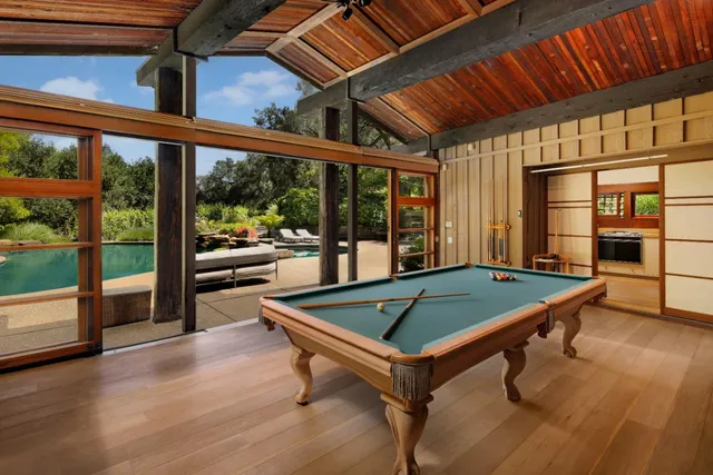 a view of a swimming pool and lounge chairs in back of the house