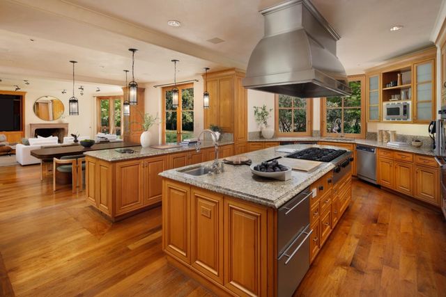 a kitchen with stainless steel appliances kitchen island granite countertop a table chairs sink and cabinets