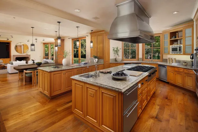a kitchen with stainless steel appliances kitchen island granite countertop a table chairs sink and cabinets