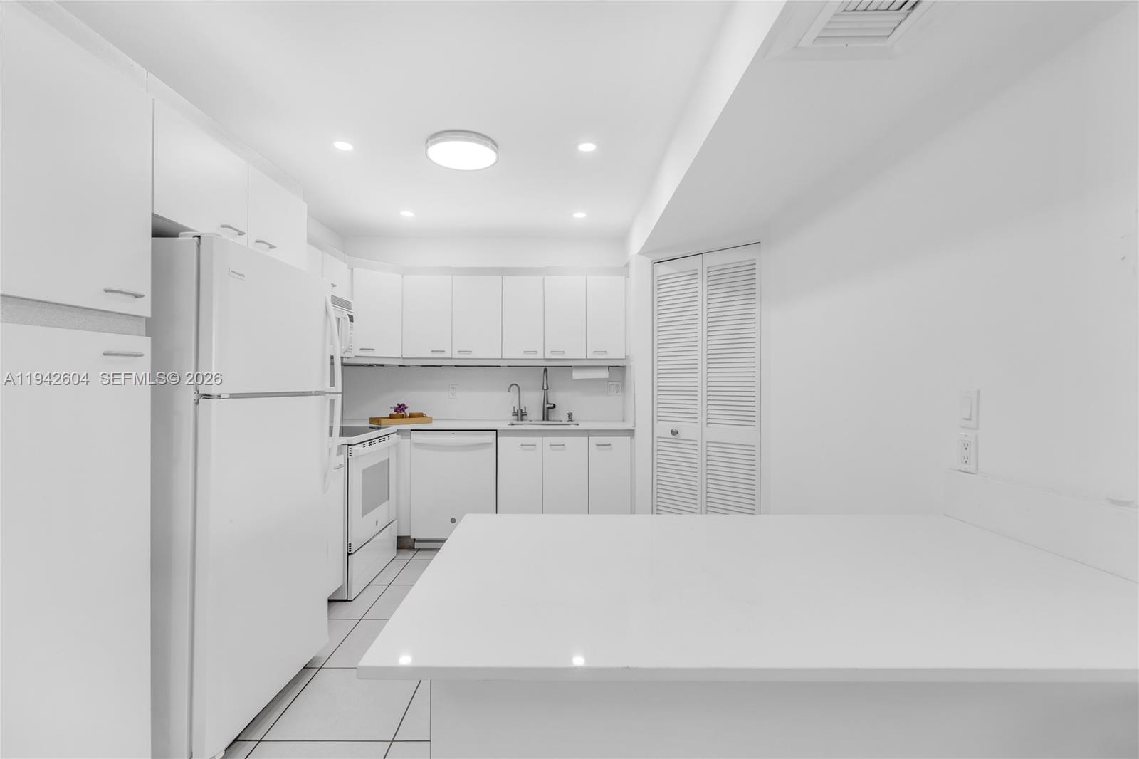 9273 Collins Avenue, Unit 503 Surfside, FL 33154 - Photo 15 of 48 a kitchen with white cabinets and refrigerator