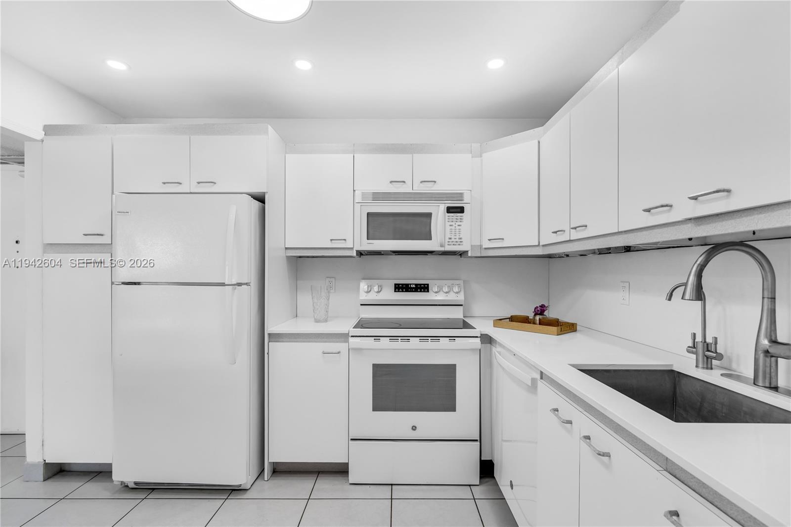 9273 Collins Avenue, Unit 503 Surfside, FL 33154 - Photo 18 of 48 a kitchen with white cabinets and white appliances