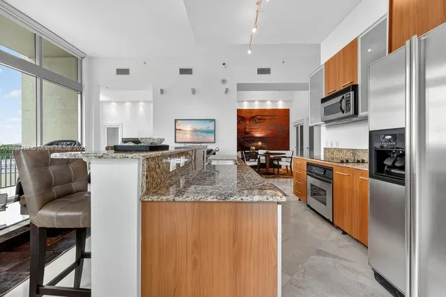 a large kitchen with stainless steel appliances granite countertop a stove top oven a sink dishwasher a dining table and chairs