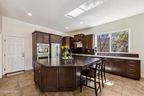 a kitchen with stainless steel appliances granite countertop a table chairs and a refrigerator