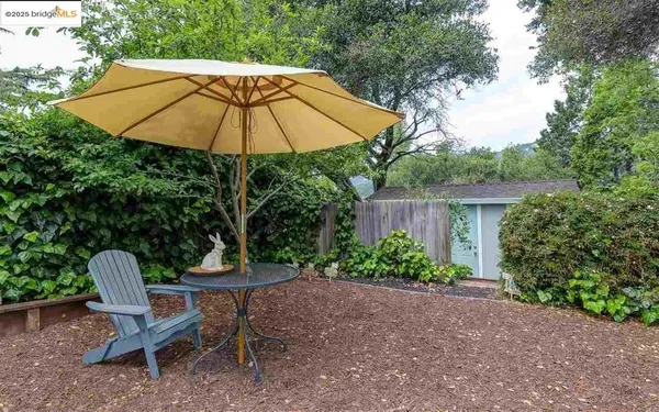 a view of a chair and table under an umbrella in backyard
