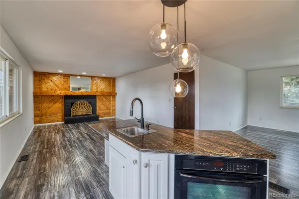 a kitchen with granite countertop a stove a sink and a wooden cabinets
