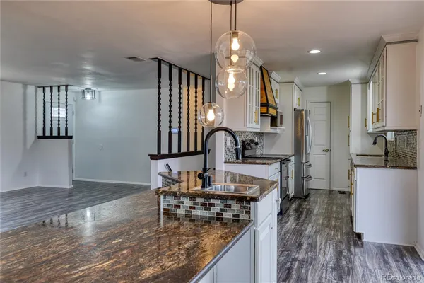 a kitchen with kitchen island granite countertop a stove a sink a refrigerator and wooden floor