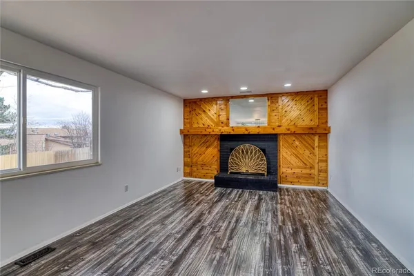 a room with wooden floor a fireplace and a window
