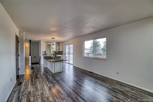 a living room with stainless steel appliances kitchen island granite countertop a refrigerator stove a sink and dishwasher a oven with wooden floor