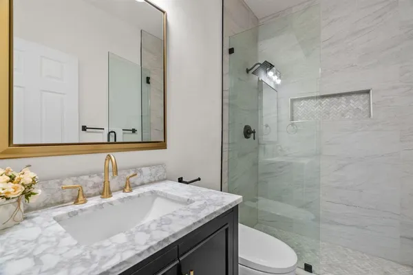 a bathroom with a granite countertop sink a toilet and shower