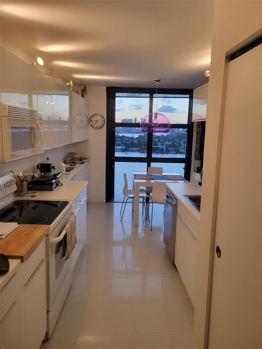 9 Island Avenue, Unit 1806 Miami Beach, FL 33139 - Photo 4 of 21 a kitchen with stainless steel appliances a stove a refrigerator a sink and white cabinets next to a window
