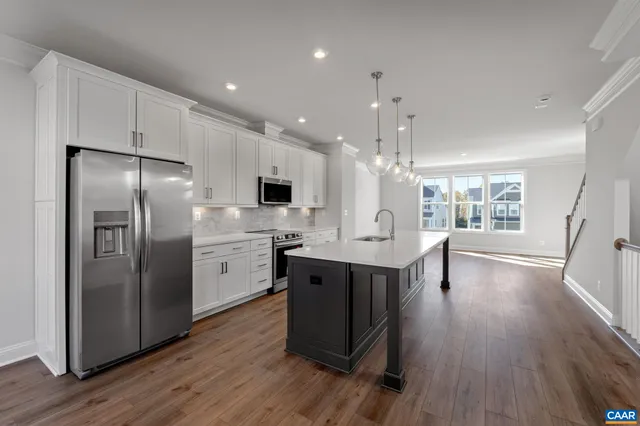 a kitchen with stainless steel appliances granite countertop a refrigerator a sink dishwasher a stove and white countertops with wooden floor